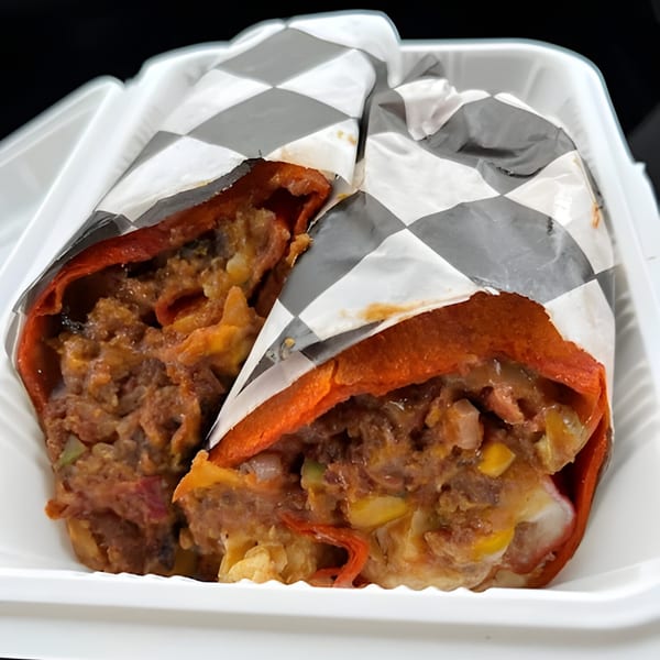 Two Mitchell's Breakfast Burritos, cut in half, revealing a hearty filling in a white container.