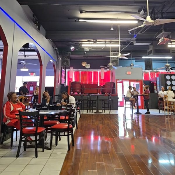Interior of Mitchell's Breakfast Burritos, with red and black decor, people dining, and a stage area.