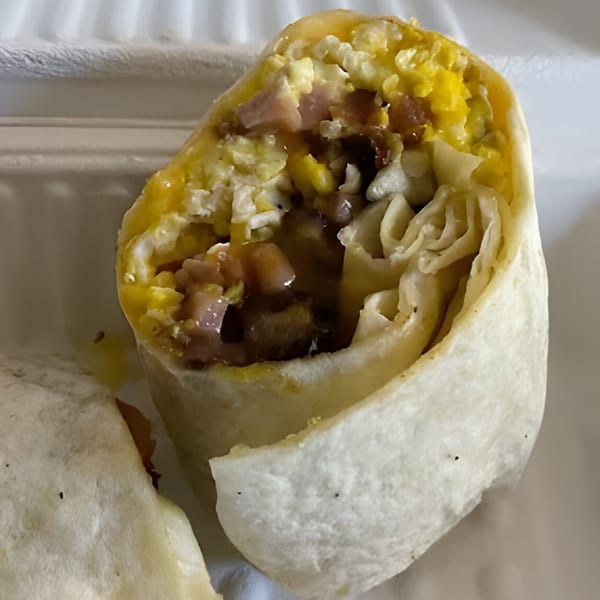 A Mitchell's breakfast burrito, cut in half, revealing eggs, ham, and other fillings.