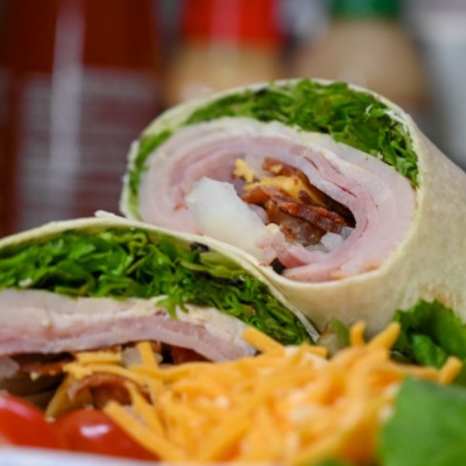 Two halves of a Mitchell's breakfast burrito, filled with ham, bacon, cheese, and lettuce.